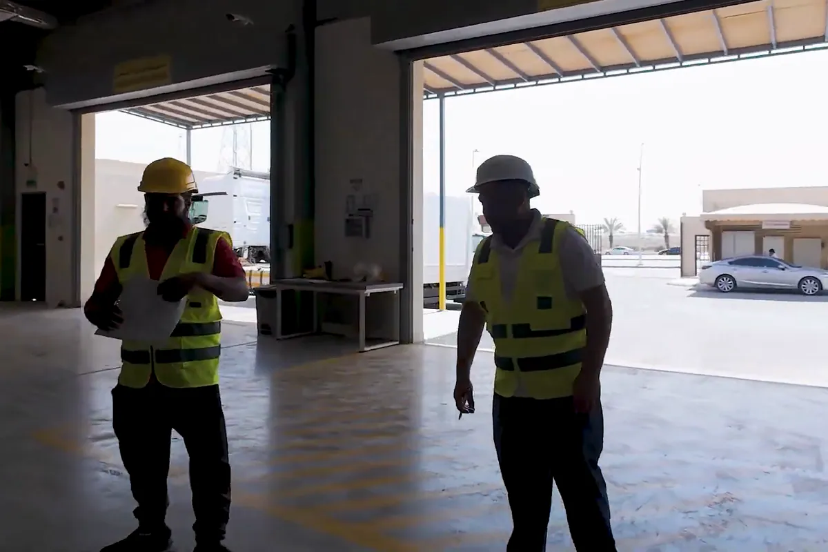 Liqa staff in safety vests and hard hats checking an inbound delivery at the warehouse dock